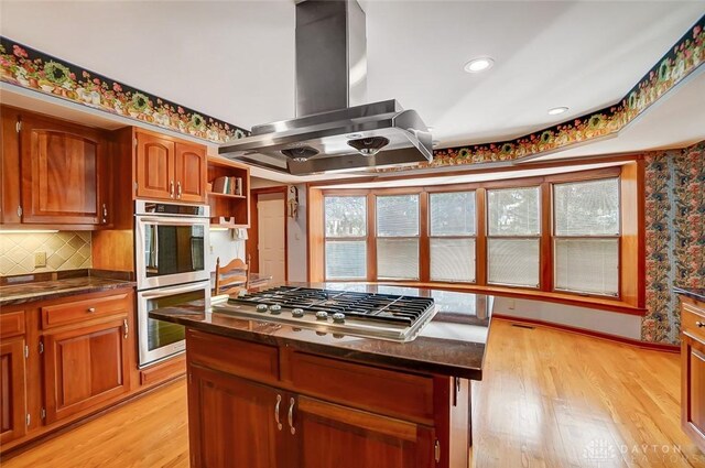 6485 Munger Rd, Dayton, OH 45459 - kitchen with stainless steel appliances, backsplash, light wood-type flooring, and island exhaust hood