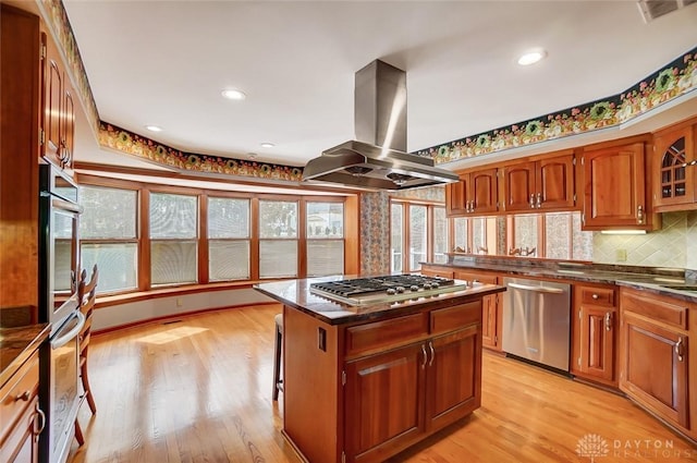 kitchen with a center island, island exhaust hood, light wood finished floors, visible vents, and appliances with stainless steel finishes