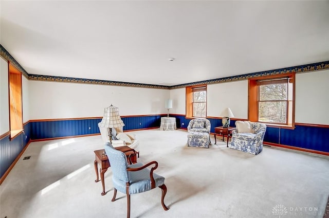 living area featuring wainscoting, carpet flooring, and visible vents