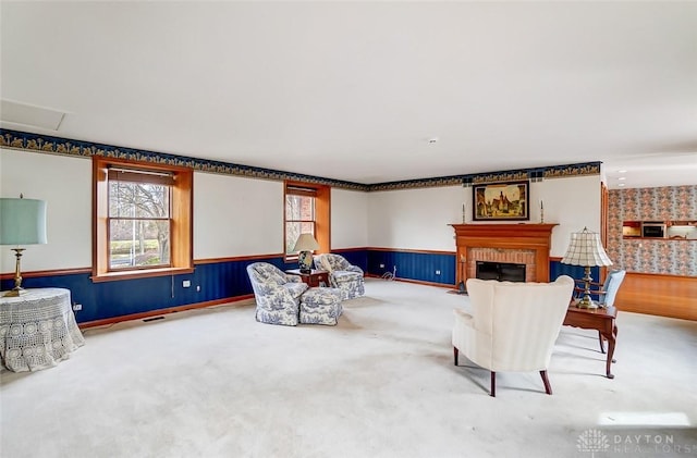 sitting room featuring a wainscoted wall, a brick fireplace, and visible vents