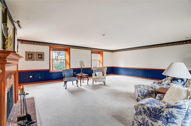 carpeted living area featuring a wainscoted wall and a fireplace