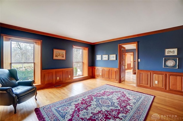 living area featuring a wainscoted wall, plenty of natural light, and wood finished floors