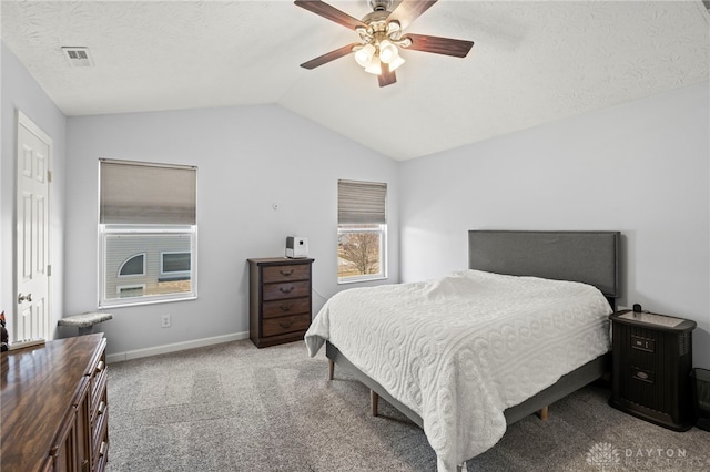 carpeted bedroom with ceiling fan, a textured ceiling, visible vents, baseboards, and vaulted ceiling