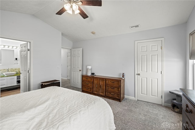 bedroom with carpet floors, visible vents, vaulted ceiling, a sink, and baseboards