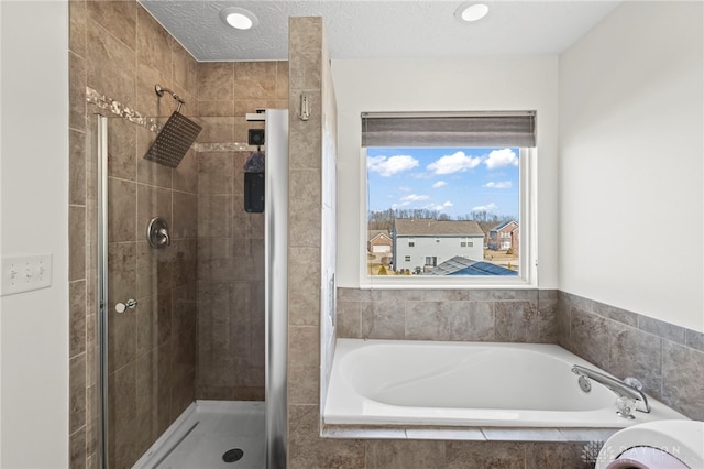 bathroom featuring a textured ceiling, a shower stall, and a bath