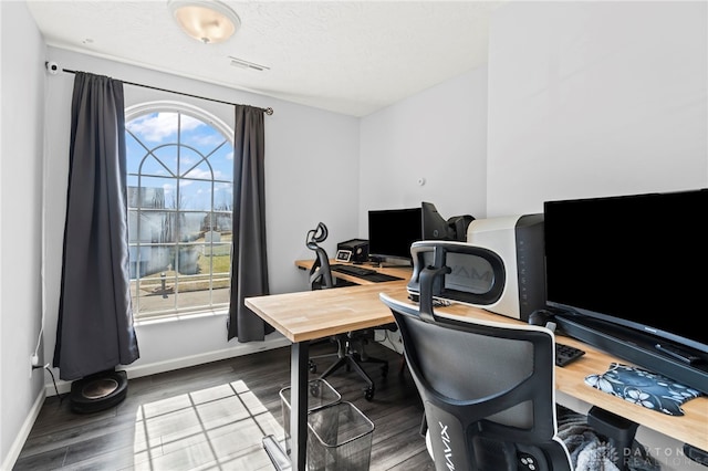 office space with a textured ceiling, wood finished floors, visible vents, and baseboards