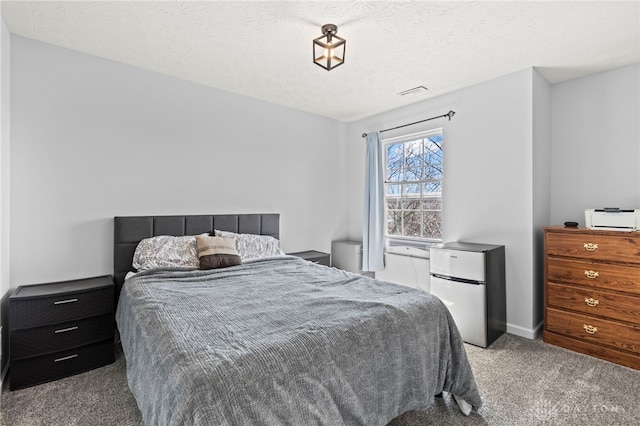 bedroom featuring a textured ceiling, carpet flooring, freestanding refrigerator, and baseboards