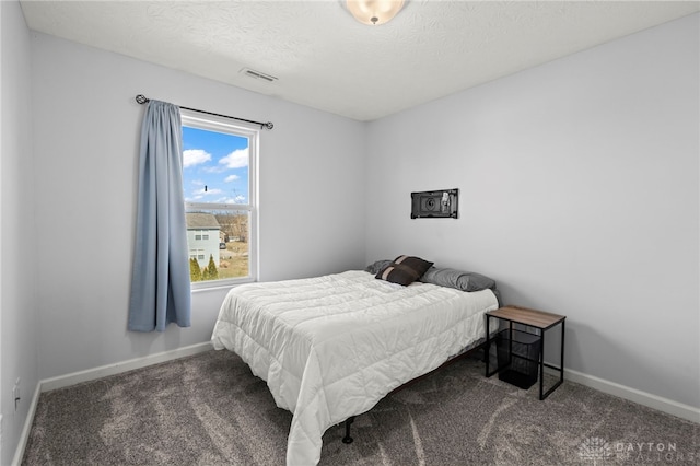 bedroom featuring a textured ceiling, carpet floors, visible vents, and baseboards