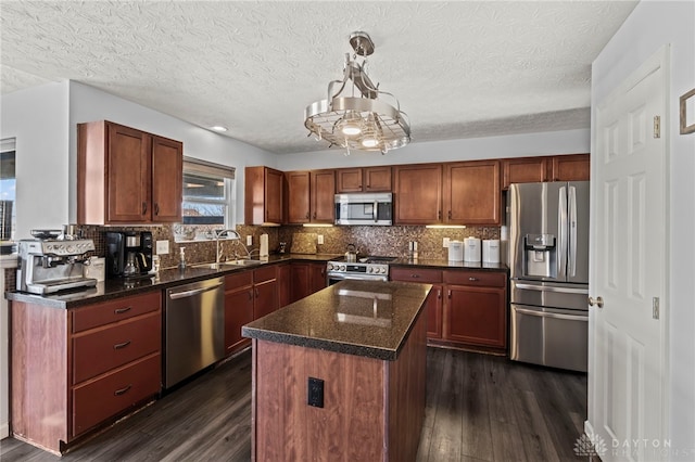 kitchen featuring tasteful backsplash, appliances with stainless steel finishes, dark wood-type flooring, a center island, and a sink