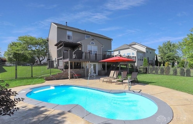 rear view of property featuring a yard, a patio area, fence, and a fenced in pool