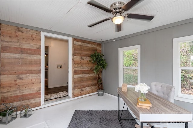 office space with finished concrete floors, ceiling fan, and wooden walls