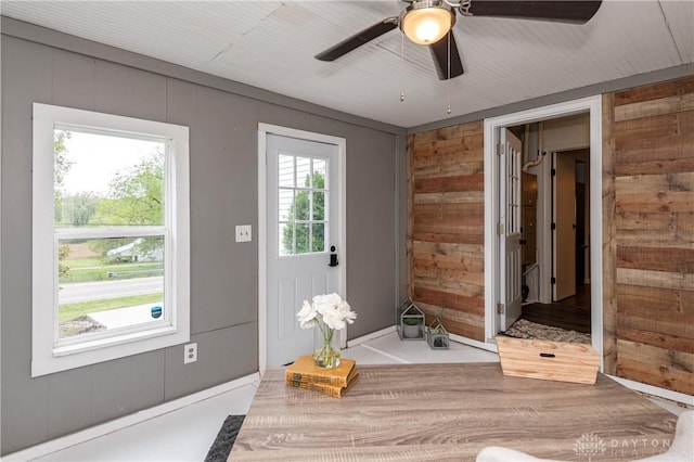 entryway with ceiling fan and wooden walls