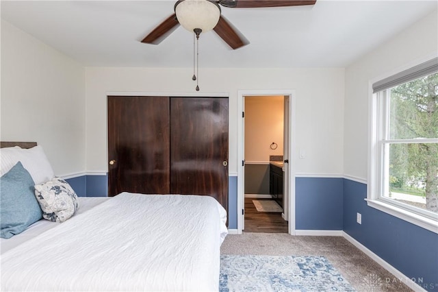 carpeted bedroom with ceiling fan, multiple windows, baseboards, and ensuite bathroom