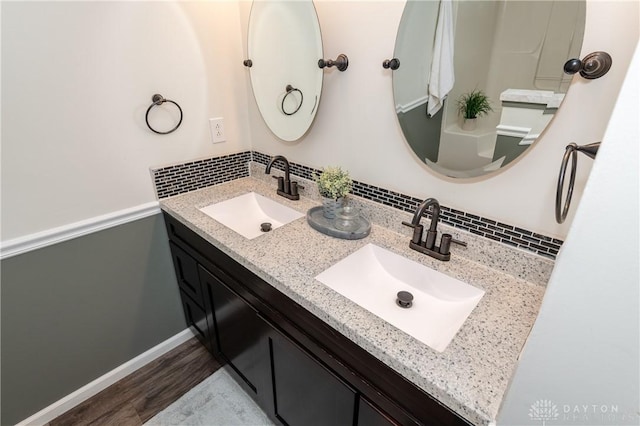 full bathroom featuring double vanity, wood finished floors, a sink, and baseboards