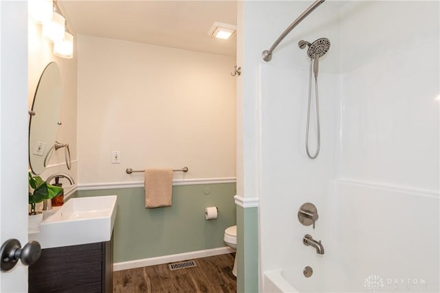 bathroom with shower / washtub combination, visible vents, toilet, vanity, and wood finished floors