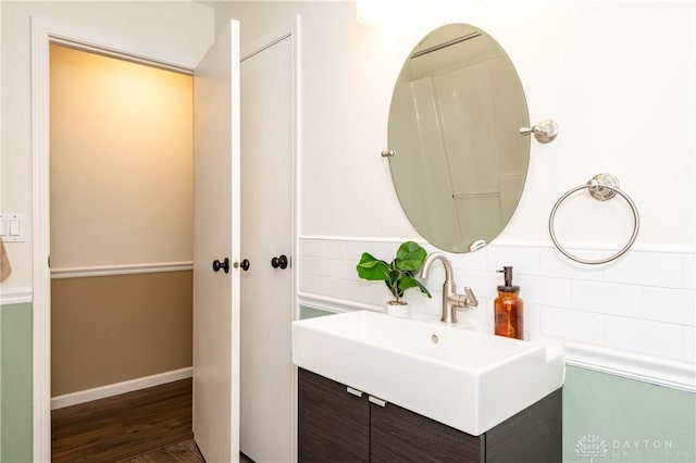 bathroom featuring baseboards, a sink, decorative backsplash, and wood finished floors