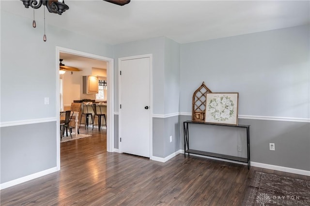 empty room featuring ceiling fan, baseboards, and wood finished floors