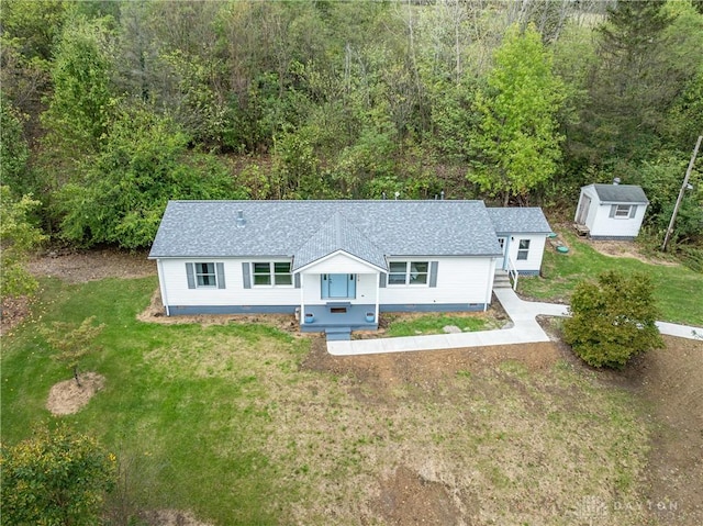 single story home with an outbuilding, a storage shed, roof with shingles, and a front yard