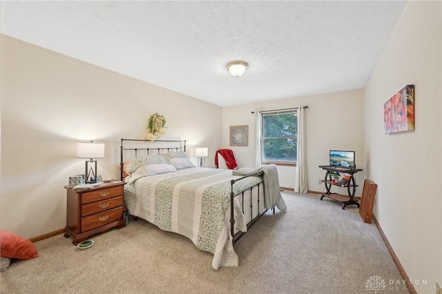 bedroom featuring baseboards, a textured ceiling, and light colored carpet