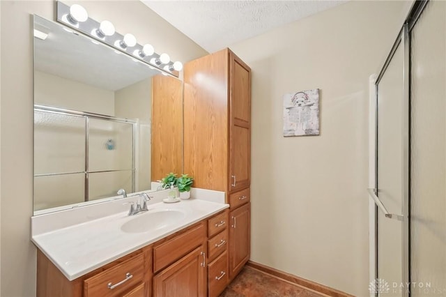 bathroom with a shower with door, vanity, and baseboards