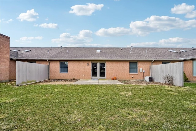 rear view of house featuring a patio, cooling unit, brick siding, fence, and a yard