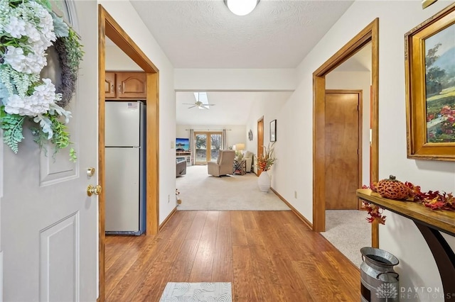 foyer entrance featuring baseboards, ceiling fan, a textured ceiling, and light wood finished floors