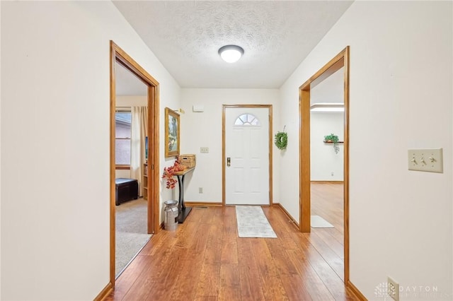 entrance foyer with light wood-style flooring, baseboards, and a textured ceiling