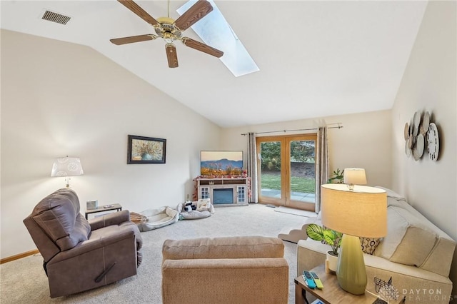 living room with carpet, a skylight, visible vents, a glass covered fireplace, and ceiling fan