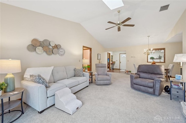 living area featuring vaulted ceiling with skylight, carpet, visible vents, and ceiling fan with notable chandelier