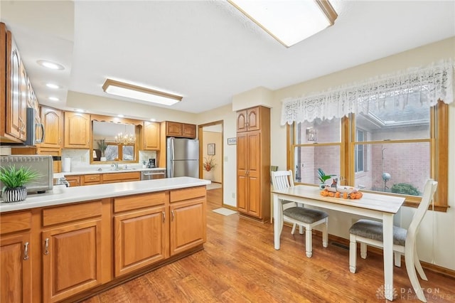 kitchen with light wood-style flooring, a sink, light countertops, appliances with stainless steel finishes, and brown cabinetry