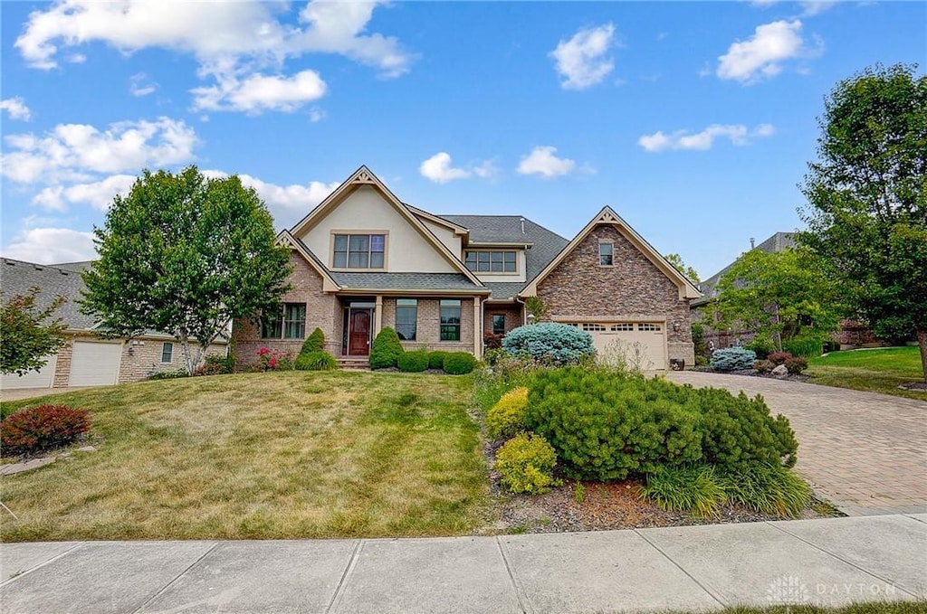 view of front of house featuring decorative driveway, an attached garage, a front lawn, and stucco siding