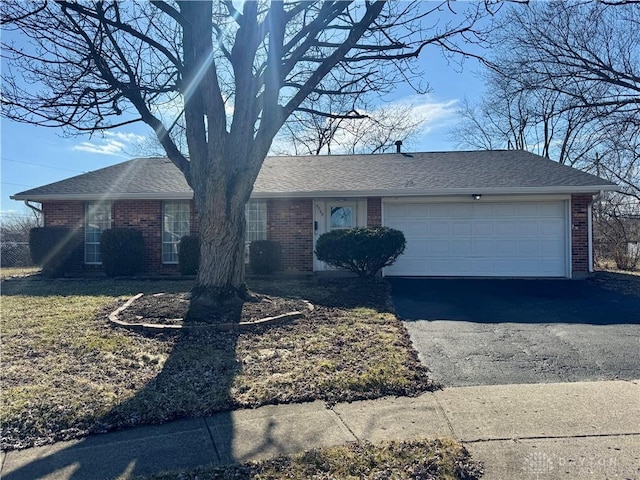 single story home featuring driveway, roof with shingles, a garage, and brick siding