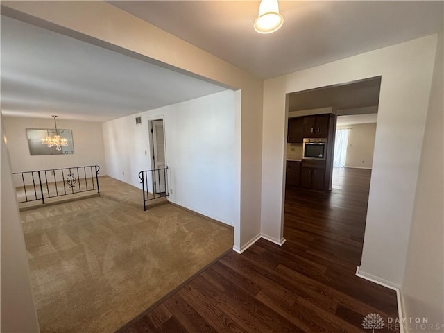 interior space with a chandelier, dark wood-style flooring, visible vents, baseboards, and dark carpet