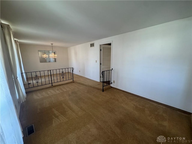 carpeted empty room featuring visible vents and an inviting chandelier