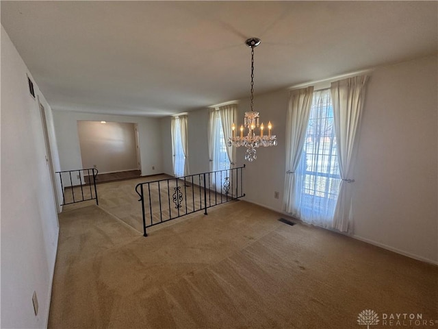 unfurnished dining area featuring carpet, visible vents, and an inviting chandelier