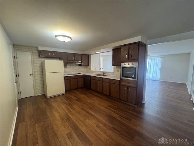 kitchen featuring dark brown cabinetry, freestanding refrigerator, light countertops, stainless steel oven, and a sink