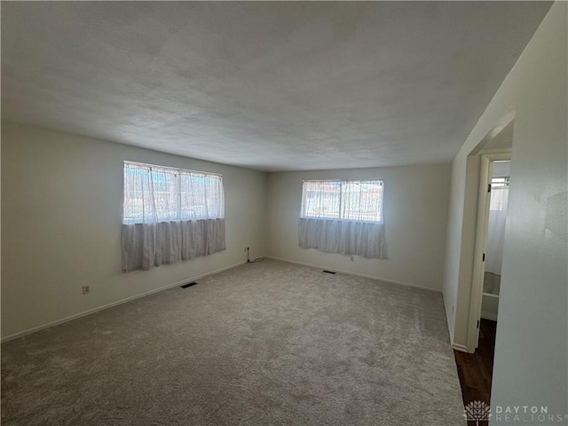 carpeted empty room featuring visible vents and baseboards