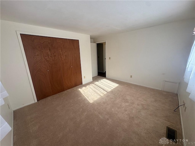 unfurnished bedroom with carpet floors, a closet, and visible vents