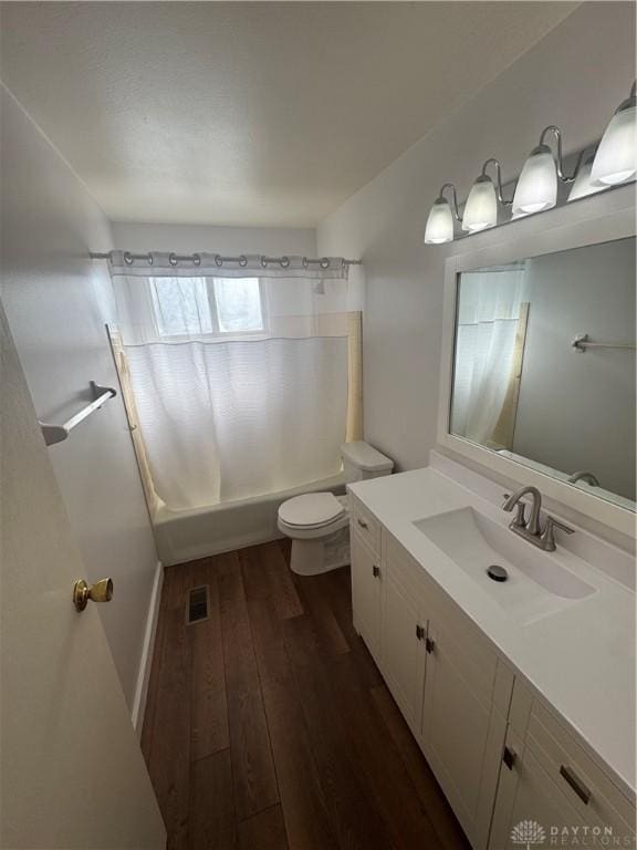 bathroom with visible vents, toilet, hardwood / wood-style floors, shower / tub combo with curtain, and vanity