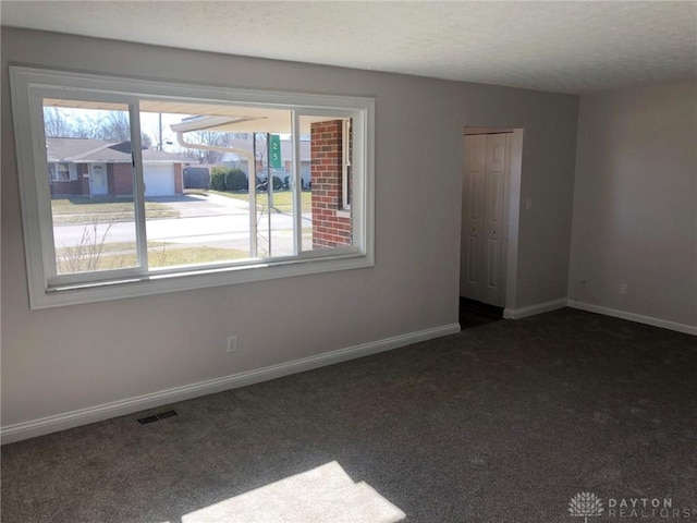 carpeted spare room with baseboards, a textured ceiling, and visible vents