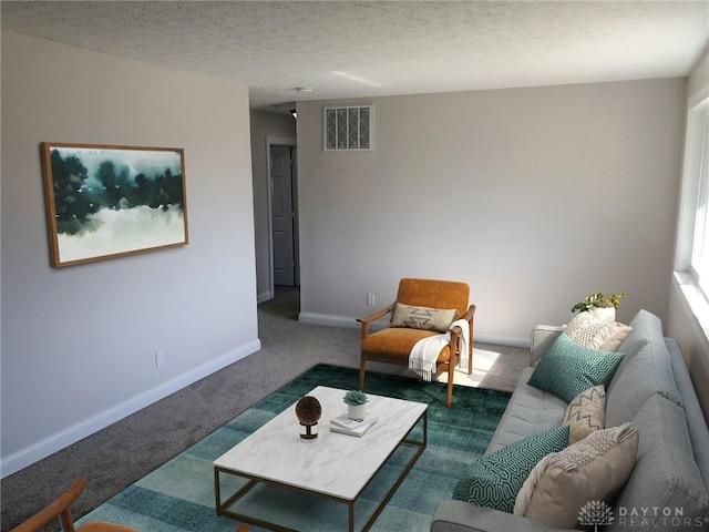 carpeted living room featuring baseboards, a textured ceiling, and visible vents