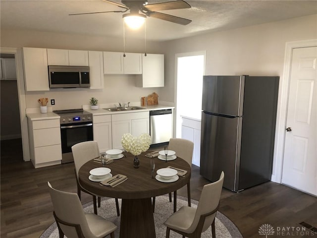 kitchen with white cabinets, ceiling fan, appliances with stainless steel finishes, and dark wood-type flooring