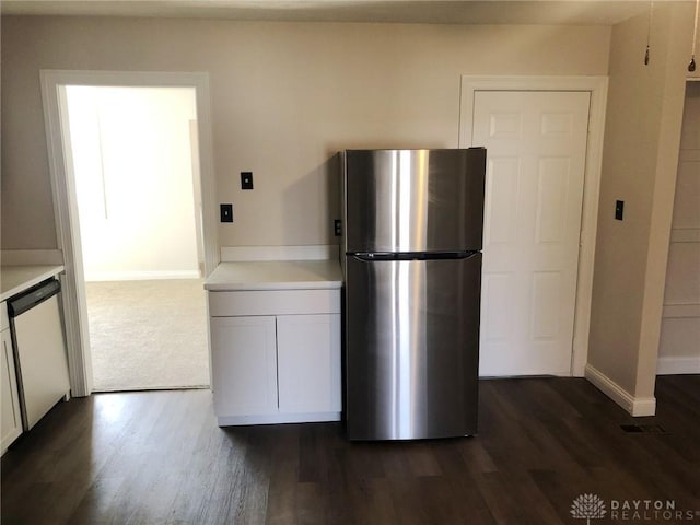 kitchen with baseboards, dishwasher, dark wood-type flooring, freestanding refrigerator, and light countertops