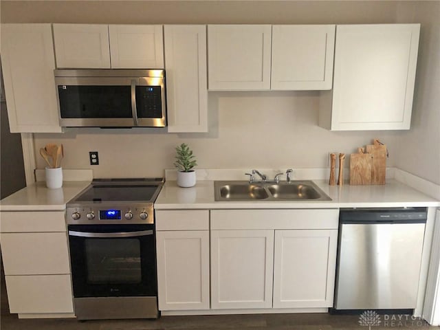 kitchen featuring light countertops, appliances with stainless steel finishes, a sink, and white cabinetry