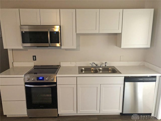 kitchen featuring stainless steel appliances, a sink, light countertops, and white cabinets