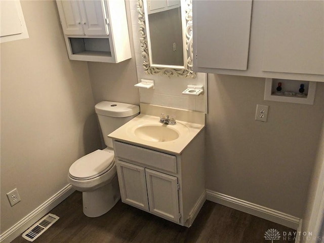 half bathroom featuring toilet, wood finished floors, baseboards, and visible vents