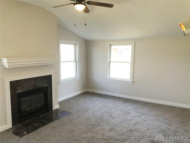 unfurnished living room featuring a premium fireplace, lofted ceiling, baseboards, ceiling fan, and carpet