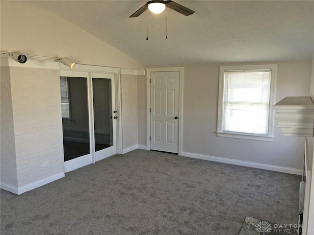 carpeted spare room featuring lofted ceiling, ceiling fan, and baseboards