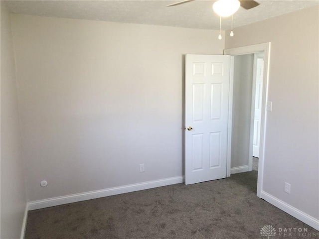 carpeted empty room featuring baseboards and a ceiling fan