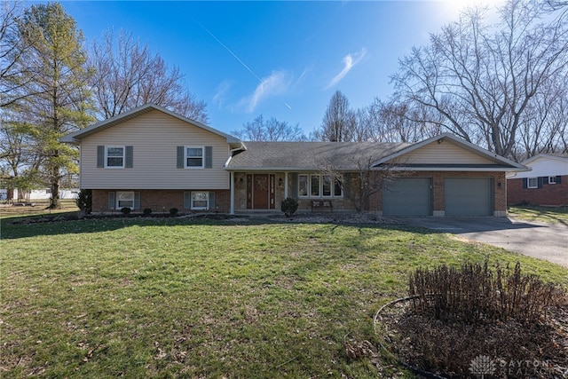 tri-level home with a front yard, concrete driveway, brick siding, and an attached garage